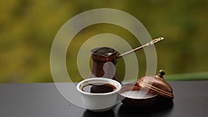 Tasty hot coffee in white coffee cup with sugar brewed in traditional turkish pot, cafe table outdoors