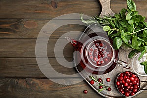 Tasty hot cranberry tea and fresh ingredients on wooden table, top view. Space for text