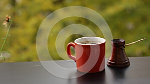 Tasty hot dark coffee brewed in traditional turkish coffee pot, cafe table on veranda