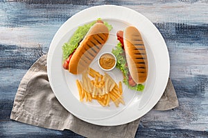 Tasty hot dogs and french fries on plate