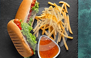 Tasty hot dogs and french fries on slate plate