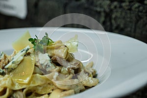 Tasty hot noodle with cream sauce with fried mushrooms and Roquefort cheese in a bar on a brick wall background. photo