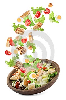 Tasty ingredients for Caesar salad falling into plate on white background