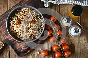 Tasty Italian spaghetti pasta with mussel, tomato and garnish on round dish and wooden plate for serving on wooden table