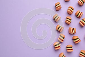 Tasty jelly candies in shape of burger on lilac background, flat lay. Space for text