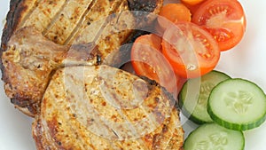 Tasty juicy fresh slices of grilled steak entrecote pork meat next to cherry tomatoes and fresh vegetables cucumbers on