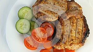 Tasty juicy fresh slices of grilled steak entrecote pork meat next to cherry tomatoes and fresh vegetables cucumbers on