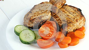 Tasty juicy fresh slices of grilled steak entrecote pork meat next to cherry tomatoes and fresh vegetables cucumbers on