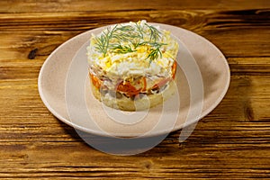 Tasty layered salad with potatoes, chicken breast, marinated mushrooms, carrots, eggs and mayonnaise on wooden table