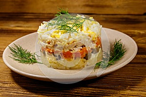Tasty layered salad with potatoes, chicken breast, marinated mushrooms, carrots, eggs and mayonnaise on wooden table