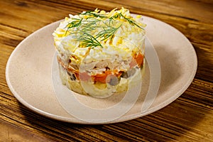 Tasty layered salad with potatoes, chicken breast, marinated mushrooms, carrots, eggs and mayonnaise on wooden table