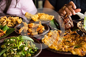 Tasty looking Indonesian food served on the table with a variety of chili sauces, rice, prawns, chicken and omlette