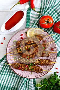 Tasty lula kebab on the plate on a white wooden table. Chopped meat on wooden skewers, grilled. Eastern cuisine.