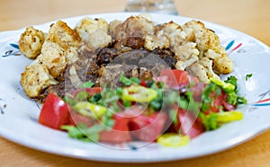 Tasty lunch on a plate. Fried meat slices, cauliflower, hot peppers, tomatoes, parsley