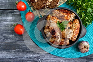 Tasty meat rolls with mushrooms in a ceramic pot on a wooden background. Top view