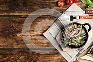 Tasty meat served with asparagus and sprouts in portioned frying pan on table, flat lay. Space for text