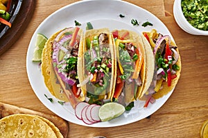 Tasty mexican tacos with beef fajita filling served with salsa and guacamole in flat lay composition photo