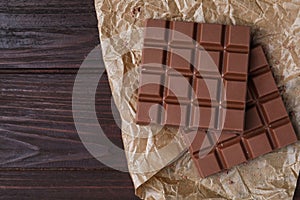 Tasty milk chocolate bars on wooden table, flat lay. Space for text