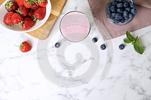 Tasty milk shake and berries on marble table, flat lay. Space for text