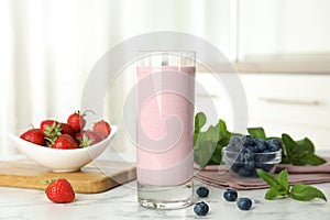 Tasty milk shake and berries on white table