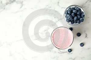 Tasty milk shake and blueberries on marble table, flat lay. Space for text