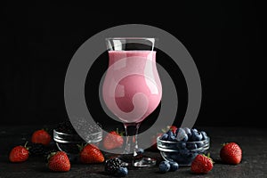 Tasty milk shake and fresh berries on slate table