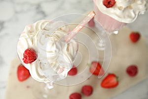 Tasty milk shake with whipped cream and berries on light table, closeup