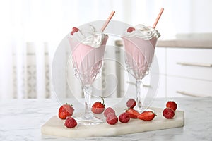 Tasty milk shake with whipped cream and berries on white marble table