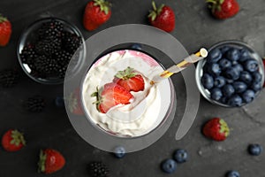 Tasty milk shake with whipped cream and fresh berries on black slate table, flat lay