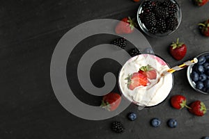 Tasty milk shake with whipped cream and fresh berries on black slate table, flat lay. Space for text