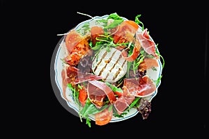 Tasty mixed salad dish with grilled camembert cheese, prosciutto ham, organic tomato and fresh green leaves. Healthy dilicious