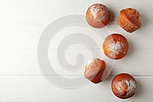 Tasty muffins on white wooden background top view