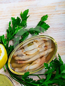 Tasty natural navajas in open tin can served with greens and lemon photo