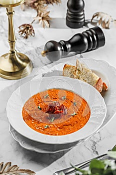 Tasty nut soup with grilled bacon and bread at the white plate on light marble background. Healthy sea food, hard light,