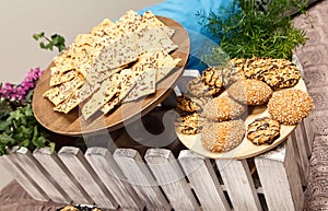 Tasty oatmeal cookies with sesame seeds on wooden boards at decorated table.