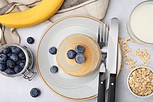 Tasty oatmeal pancakes and ingredients on grey table, flat lay