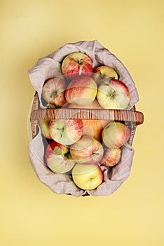 Tasty Organic Apples and Small Pumpkin in Basket on Yellow Background Vertical Top View Harvest Time Autumn Fruits in Basket