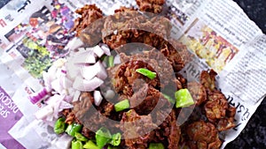 Tasty pakode with fried chilly and onion, served in Gujarati newspaper Indian street food called tikadi