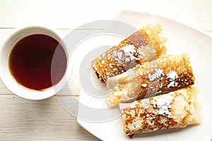 Tasty pancake rolls and tea cup on wooden table, top view