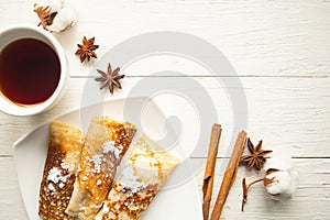 Tasty pancake rolls and tea cup on wooden table, top view