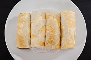 Tasty pancakes with cottage cheese in a white plate isolated on a black background.