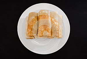 Tasty pancakes with cottage cheese in a white plate isolated on a black background.