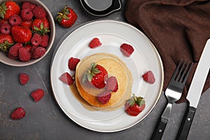 Tasty pancakes served with fresh berries and honey on grey table, flat lay