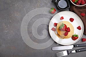 Tasty pancakes served with fresh berries and honey on grey table, flat lay. Space for text