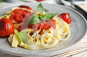 Tasty pasta with tomatoes and basil on wooden table, closeup