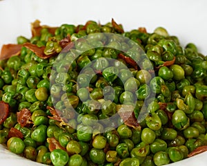 Tasty Peas with ham in a white dish. Close up view