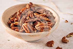 Tasty pecan nuts in a bowl on beige background