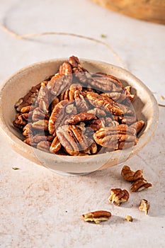 Tasty pecan nuts in a bowl on beige background