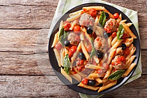 Tasty penne with meatballs, olives and tomato sauce closeup. Horizontal top view