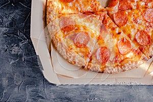 Tasty pepperoni pizza in a box on brown concrete background. Top view of hot pepperoni pizza. With copy space for text. Flat lay